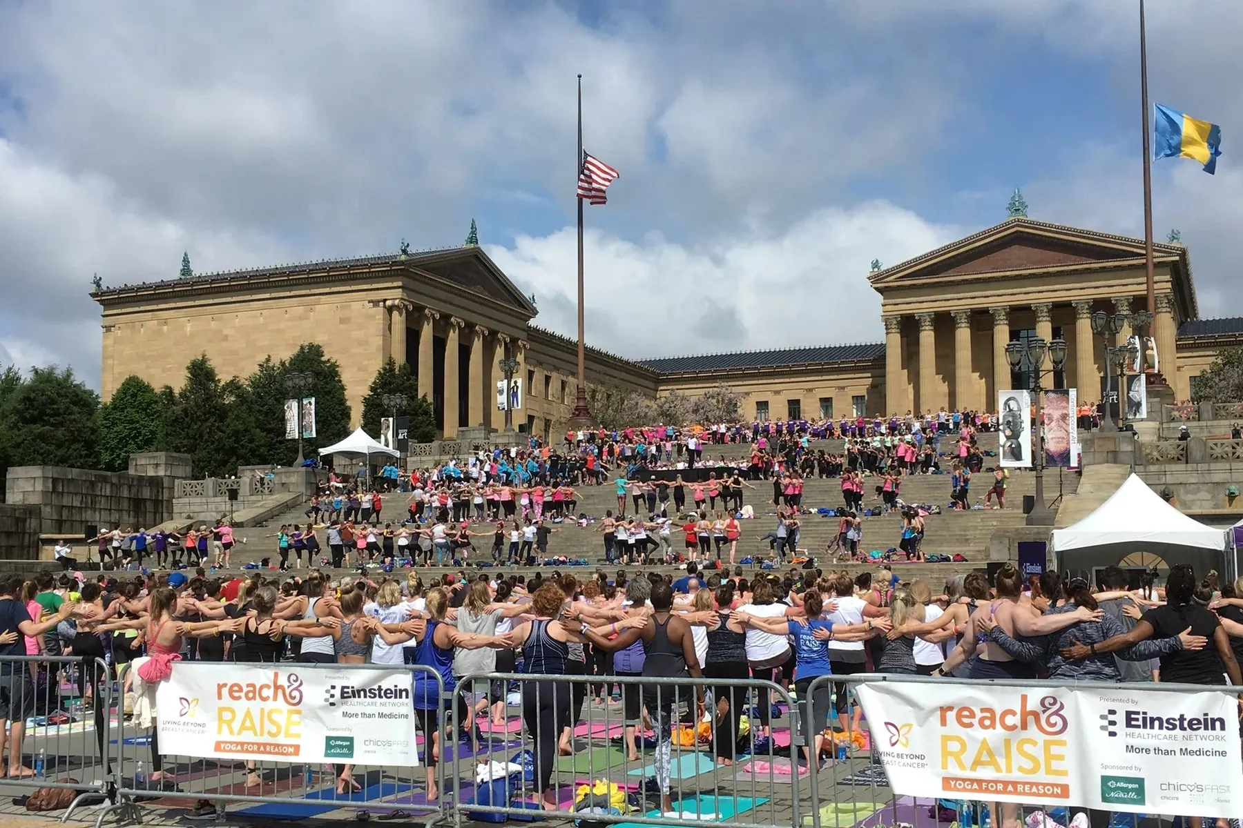 Hundreds of participants stretching in unison on the steps of the Philadelphia Museum of Art during the Reach & Raise yoga event.